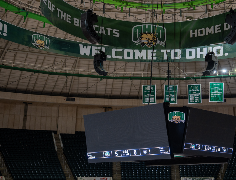 ou_convocation_carousel-1 Center-hung scoreboard and speaker arrays beneath "Welcome to Ohio" banners inside the Convocation Center